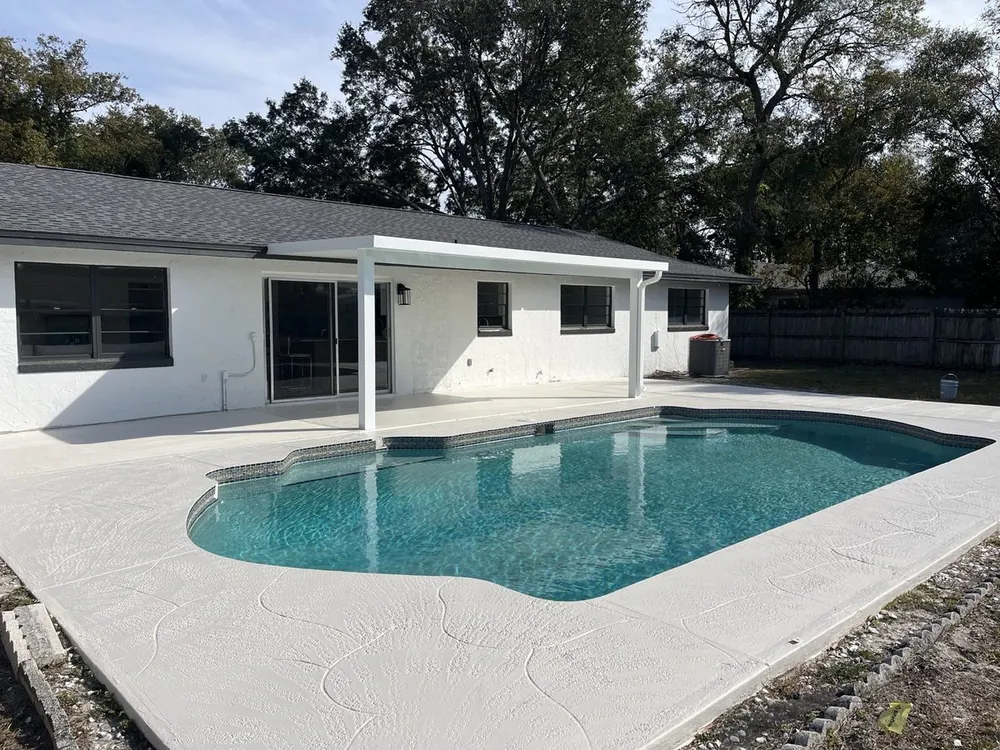 Screened backyard pool with a freshly finished paver deck
