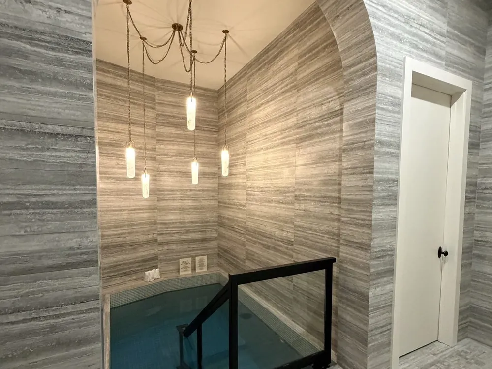 Spa-style walk-in shower framed by an arched stone-tile alcove
