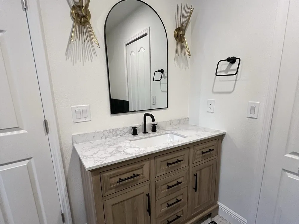 Powder bath with an arched mirror, wood vanity and designer sconces